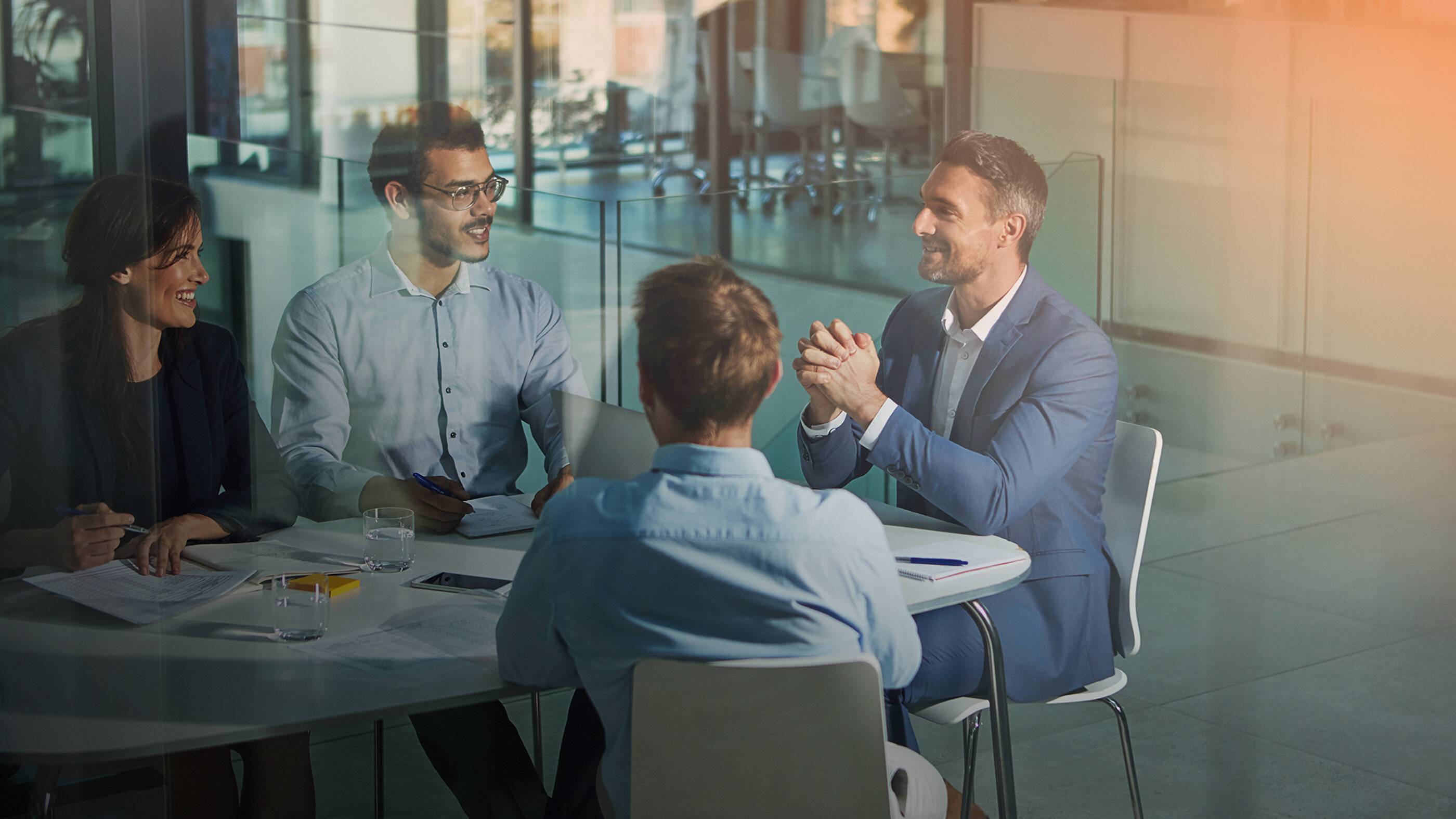 Drei Männer im Geschäftsgespräch an einem Tisch in modernem Büro